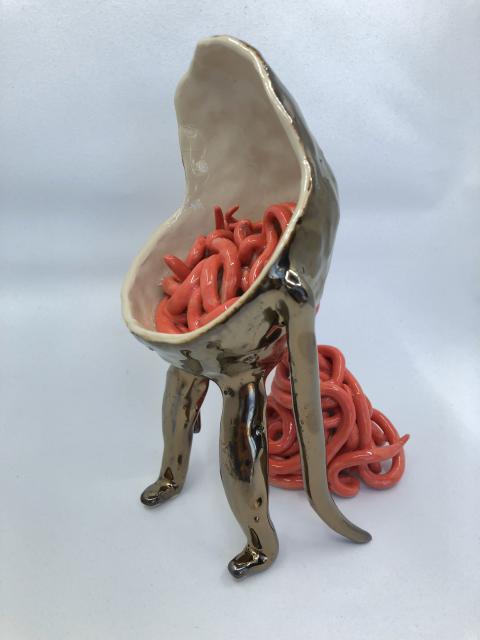 A ceramic sculpture of a creature, filled with strange pink noodles 