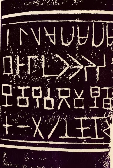 A crooked, shottily-made linocut print of four rows of eight sharp characters, like runes, but as if carved by a child.
