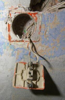 Power socket in 1970s style hanging from a hole in the wall.
Notice it is not grounded.