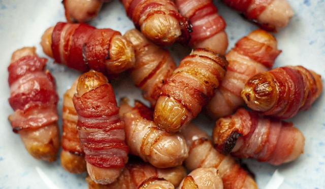 Birds eye view of cooked pigs in blankets in a bowl