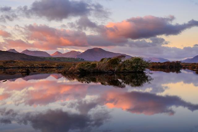 Pink clouds reflecting off a still lake at sunset.
