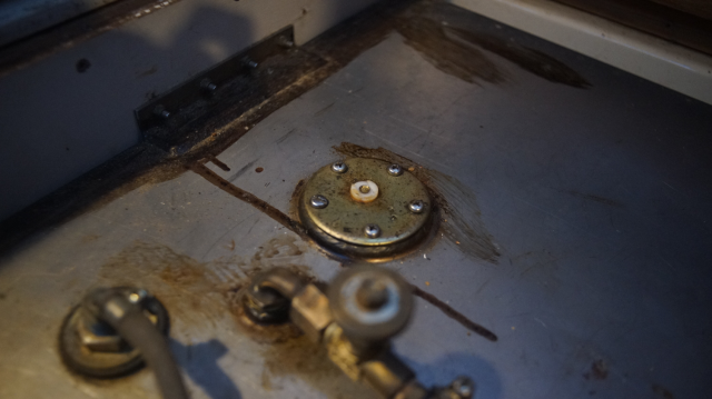 Old fuel gauge cap on a stainless steel tank.