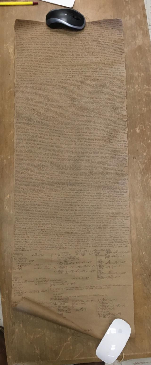 Color photo of the Magna Quanta, a handmade copy of the Magna Carta with a quantum mechanics homework assignment written at the end. Unrolled it was about three feet long. It is written on brown parchment.