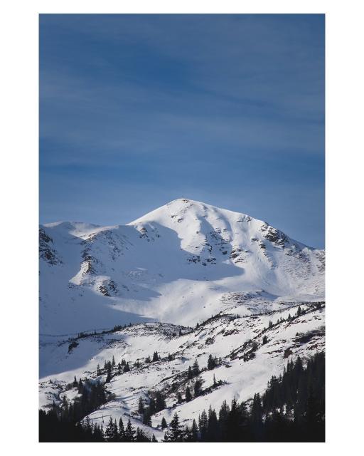 EN: The picture shows a snow-covered mountain landscape with one central peak. The mountain slopes are partly forested.

DE: Das Bild zeigt eine schneebedeckte Berglandschaft mit einem zentralen Gipfel. Die Berghänge sind teilweise bewaldet.
