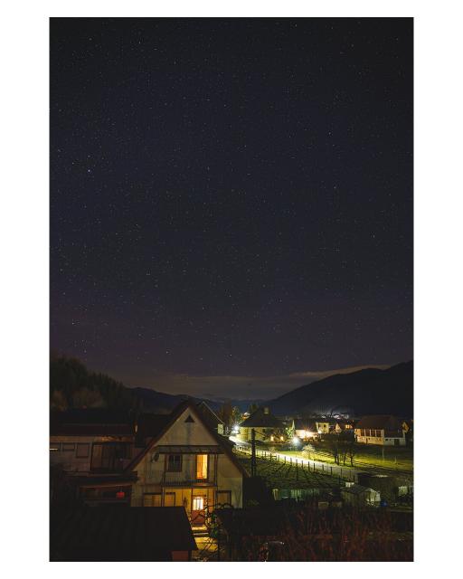 EN: Image shows illuminated village at night in front of a mountain landscape. There are many stars in the sky.

DE: Bild zeigt bei beleuchtete Ortschaft bei Nacht vor einer Berglandschaft. Am Himmel stehen viele Sterne.