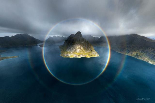 The featured image shows two complete circular rainbows centered on a mountainous island.