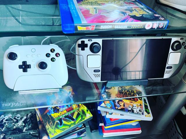 8bitdo ultimate wireless white controller next to a steam deck with a dbrand skin on