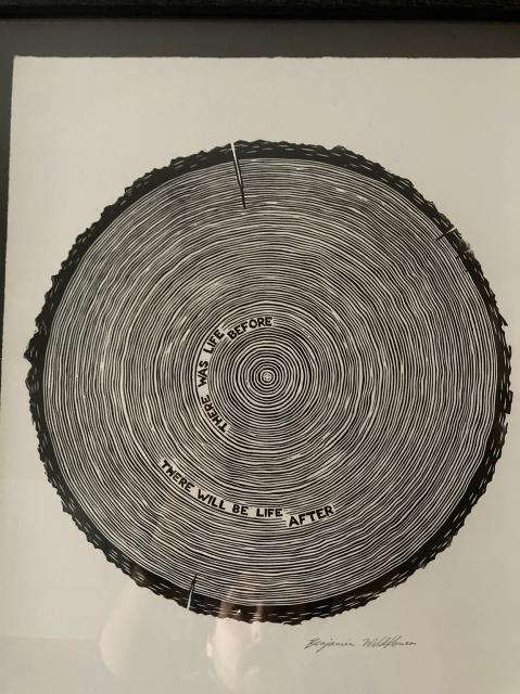 A linoleum cut print of a tree cookie with the words”there was life before; there will be life after” amongst the tree rings