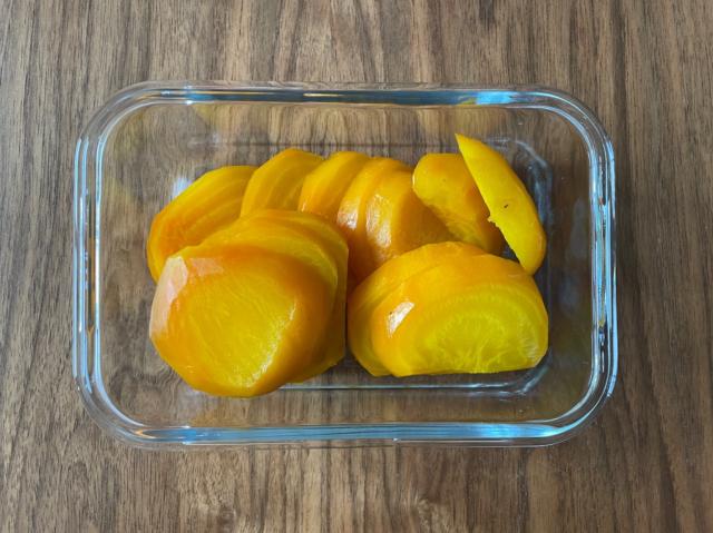 Roasted, peeled and sliced golden beets in glass container 