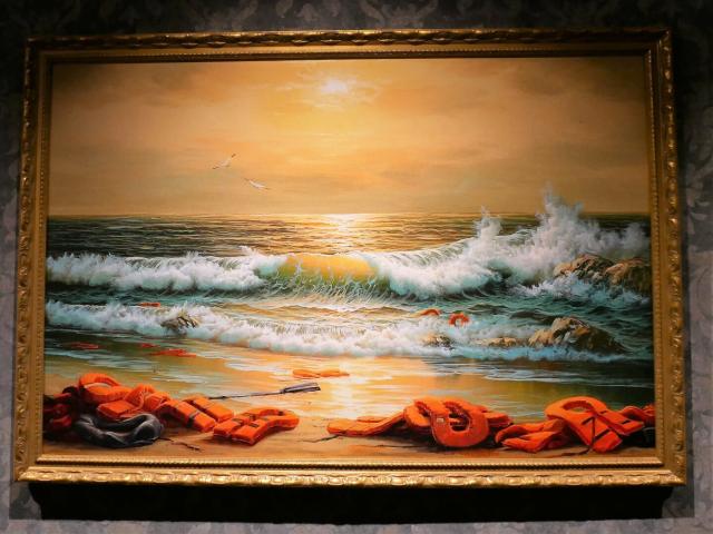 A beautiful painting of the sea. The surf is visible, two seagulls fly over the water. The sky is golden yellow.
Life jackets lie on the shore ... without people.