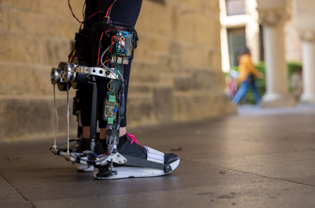 A close up side view of a boot-style exoskeleton worn over the lower leg. Raspberry Pi and various wires and HATs are visible