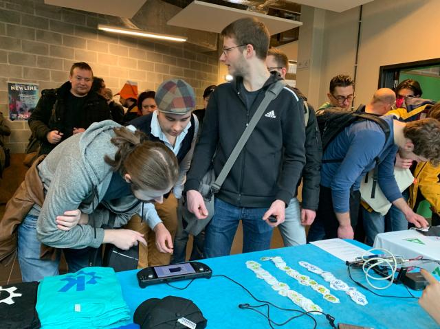 Attendee's check out Plasma-enabled devices and merch at KDE's FOSDEM booth.