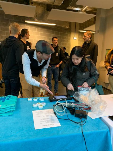 A KDE community member describes showcases Plasma on the Steam Deck to a visitor to KDE's FOSDEM booth.