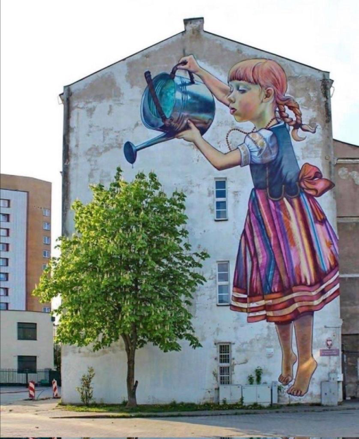 It's a four-storey gable wall painted with a young red-headed girl holding a watering-can over a living tree in a patch of grass adjacent to the wall.