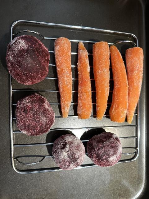Four beets and five carrots dusted with koji, sitting on a rack in a deep tray